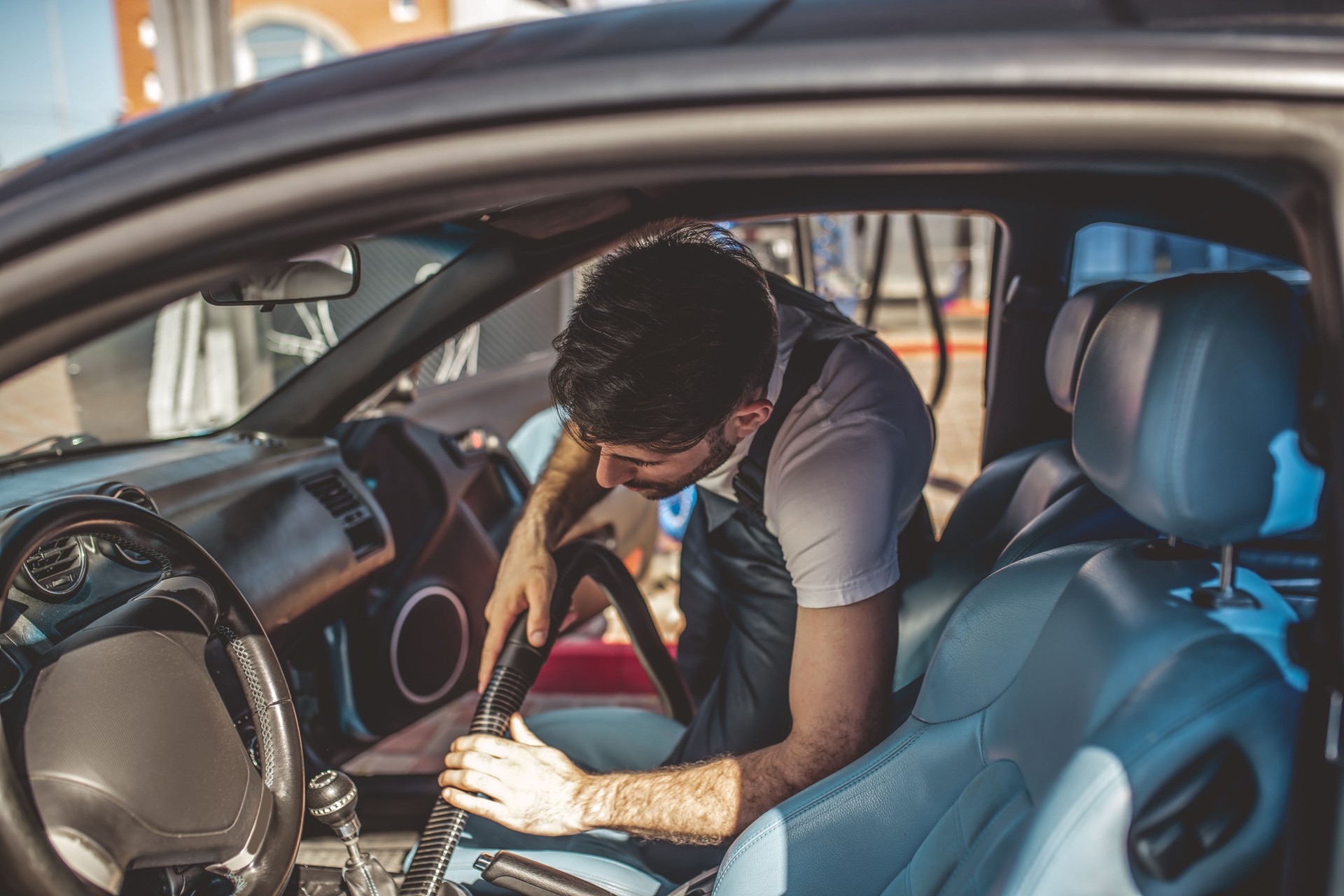 Auto detailer vacuum-cleaning a dirty car interior